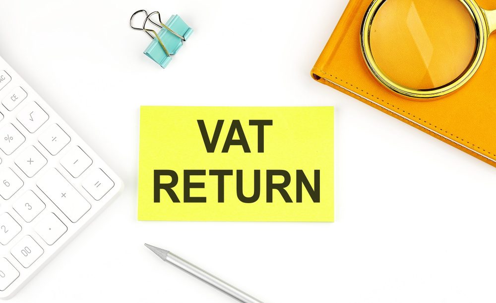 Sticker with the text VAT RETURN on white background, near calculator and notebook